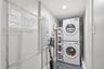 Laundry space featuring a stacked washer and dryer unit, recessed lighting, and wood-finish flooring