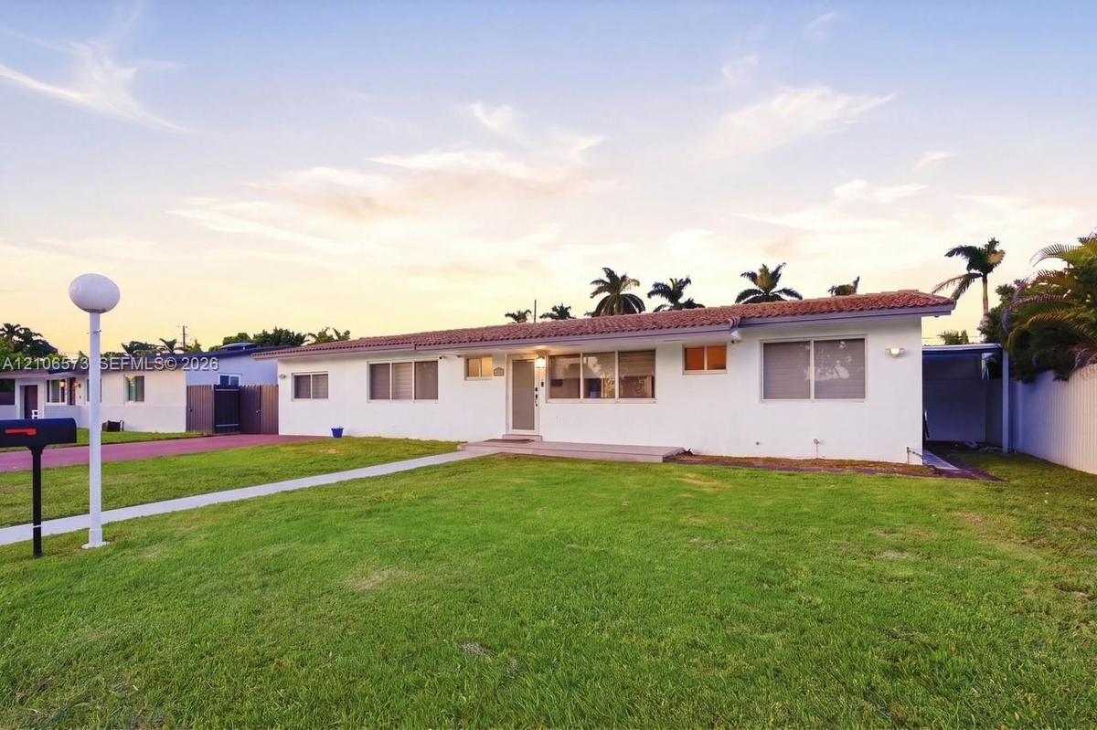 Single-story residence featuring a stucco exterior, clay tile roofing, expansive front lawn, and a paved driveway