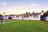Single-story residence featuring a stucco exterior, clay tile roofing, expansive front lawn, and a paved driveway