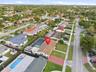 Aerial perspective featuring a screened-in swimming pool, a composition shingle roof, and a paved driveway