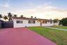 Single-story residence featuring a tile roof, light-colored exterior finish, expansive paved driveway, and manicured lawn