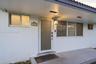 Exterior entry featuring a covered concrete porch, a frosted glass-panel front door, horizontal sliding windows, and a structured tile roofline