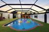 Screened-in pool area featuring brick coping, synthetic turf surfacing, and a built-in outdoor wet bar