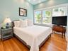 Wood-finish flooring, recessed ceiling lighting, and expansive triple-window configuration with white trim