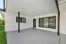 Covered patio featuring an aggregate concrete floor, dark-finished structural support columns, a glass-panel entry door, and large-format multi-pane w