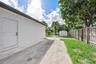 Exterior area featuring a concrete side patio, wood-slat privacy fencing, a storage shed, and mature trees