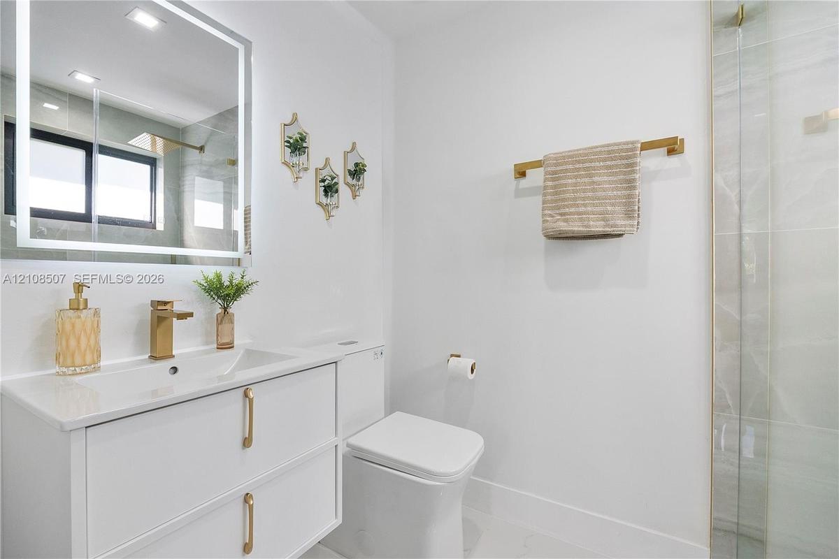 Modern floating vanity with a smooth countertop, integrated rectangular sink, and gold-finish hardware