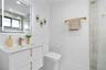 Modern floating vanity with a smooth countertop, integrated rectangular sink, and gold-finish hardware