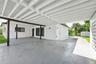 Covered carport featuring an exposed beam ceiling, smooth-finish concrete flooring, and a decorative concrete block privacy screen