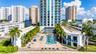 High-rise residential exterior featuring a paved pool deck, custom-shaped swimming pool, integrated landscaping, and private balconies