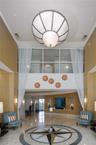 Grand entrance lobby featuring double-height ceilings, a large spherical pendant light, stone flooring with an inlaid compass rose medallion, wood-pan