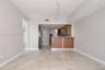 Open concept floor plan featuring light-toned tile flooring, wood-finish cabinetry, a peninsula breakfast bar, and stainless steel appliances