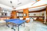 Large recreation room featuring stone tile flooring, built-in wet bar with stone countertop, wood-panelled accent walls, integrated ceiling fans, and 