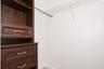 Built-in wood-finish shelving unit with three drawers featuring metallic hardware, paired with an overhead metal closet rod and wire shelving