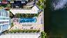 Aerial perspective of a waterfront pool deck featuring a geometric paved patio, swimming pool, in-ground spa, and mature palm trees