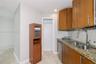 Kitchen area featuring wood cabinetry, stone countertops, double-basin undermount sink with a gooseneck faucet, stainless steel dishwasher, and tile f