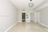Neutral-toned room featuring large-format tile flooring, modern sculptural pendant lighting, and multiple interior door entries with panel detailing
