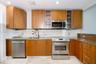Kitchen featuring wood-finish cabinetry, stone-surface countertops, stainless steel appliances, glass-front upper cabinet doors, and recessed ceiling 