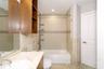 Bathroom featuring wood-finish cabinetry, stone-surface vanity countertop with an integrated basin, floor-to-ceiling tile surround, and built-in shelv