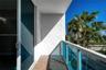 Private balcony featuring textured stucco walls, tiled flooring, and a glass-paneled railing with a metal frame