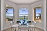 Bay window featuring large-format tile flooring, a circular LED pendant light, and triple-pane windows showcasing the pool, patio, and lakefront