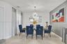 Dining space featuring oversized ceramic tile flooring, a neutral color palette with a grey accent wall, and a multi-spoke sunburst-style overhead lig