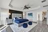 Spacious room featuring a recessed tray ceiling, wood-finish flooring, and a dramatic dark accent wall