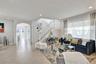 Open-concept floor plan featuring tile flooring, a prominent staircase with white balusters, an arched architectural entryway, and large windows with 