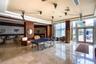 Common area featuring polished stone flooring, recessed ceiling tray detailing, wood-paneled walls, and expansive floor-to-ceiling glass panel doors