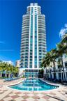 High-rise residential tower featuring wrap-around balconies and floor-to-ceiling glass windows, accented by a centered ground-level pool with tile dec