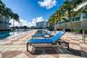 Swimming pool with geometric paver decking, surrounding palm trees, and waterfront bulkhead