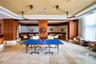 Open-concept common space featuring polished stone flooring, custom wood-panel wall treatments, integrated tiered ceiling lighting, and dual industria