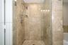 Walk-in shower featuring floor-to-ceiling stone tile, a glass enclosure, and a multi-setting handheld shower fixture