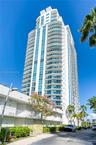 High-rise building featuring a white concrete facade, tinted glass windows, and wrap-around balconies on each level