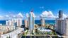 High-rise condominium tower featuring private balconies, integrated glass exterior detailing, and a ground-level swimming pool