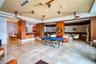 Large common area featuring natural stone tile flooring, wood-paneled columns, built-in bar with stone countertop, recessed lighting, and dual ceiling