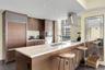 Kitchen featuring wood-finish cabinetry, stone-surface countertops, stainless steel appliances, stainless steel range hood, and recessed lighting