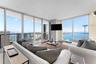 Floor-to-ceiling glass walls, expansive balcony with metal railing, and neutral tile flooring