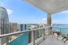 Covered private balcony featuring tile flooring and a glass railing