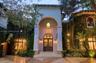 Mediterranean-inspired exterior featuring a grand arched entryway, stucco facade, decorative iron-caged pendant lighting, and stone steps leading to d