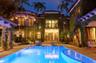 Mediterranean-style estate featuring an ivy-clad exterior, multi-level balconies, stone-paved patio, and a rectangular in-ground swimming pool with an