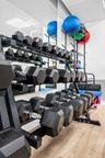 Full-length wall mirror, wood-finish flooring, and multi-tier metal storage racks featuring organized heavy-duty hex dumbbells