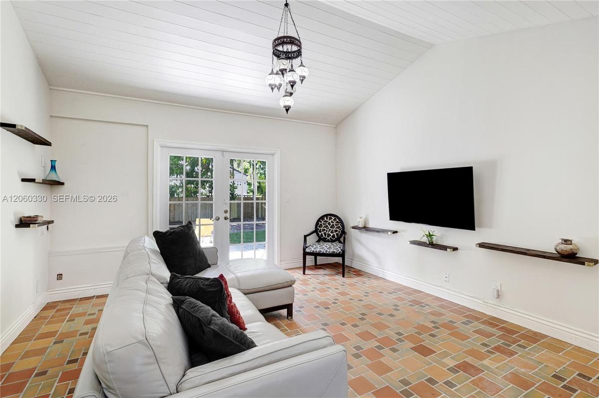 Vaulted ceiling with plank detailing, multi-tone ceramic tile flooring, decorative multi-light pendant fixture, and glass-paneled French doors