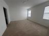 Interior space featuring neutral-toned carpeting, high-contrast white wall finishes, and dual windows equipped with horizontal roller shades
