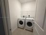 Utility room featuring neutral tile flooring, white interior walls, and wall-mounted wire shelving