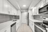 Kitchen featuring white shaker-style cabinetry, white countertops, gray subway tile backsplash, stainless steel appliances, and tile flooring