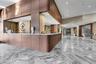 Lobby area featuring polished natural stone flooring in a herringbone pattern, wood-panelled custom reception desk with a solid surface countertop, an