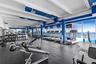 Fitness center featuring floor-to-ceiling windows with ocean scenery, exposed white beam ceilings, industrial-style exposed ductwork, and resilient ru