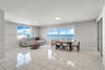 Open-concept living space featuring high-gloss tile flooring, floor-to-ceiling windows, and panoramic ocean water scenery