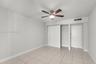 Neutral-toned room featuring large-format tile flooring, a multi-blade ceiling fan with integrated lighting, a sliding-door closet, and a contemporary